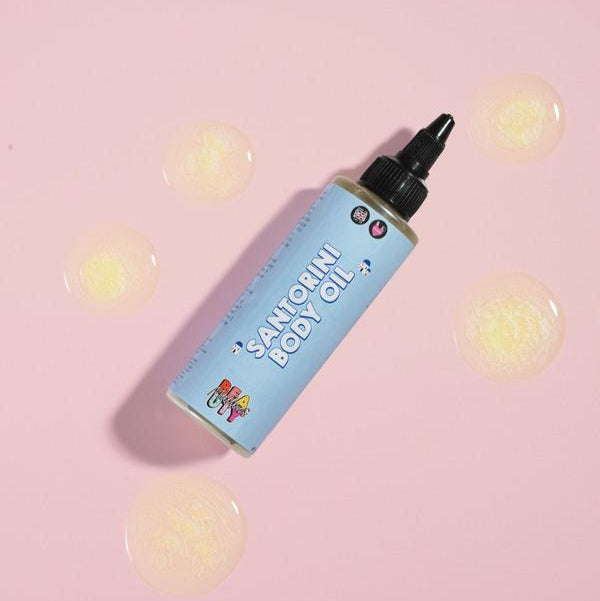 Santorini Body Oil in a bottle on a pink background
